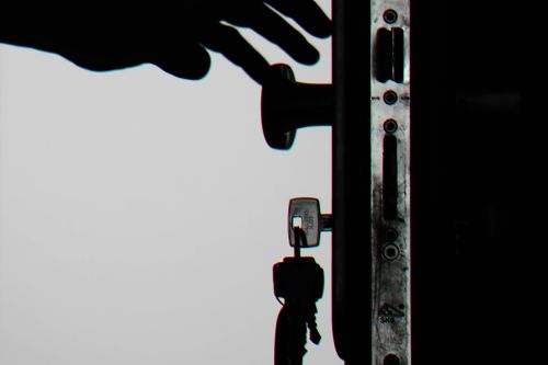 Silhouette of a hand about to open a door with keys in lock, symbolizing security.